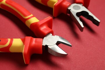 Two pliers on red background, closeup view