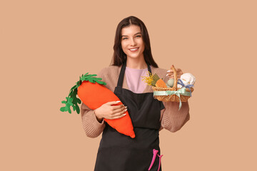 Poster - Happy female hairdresser with Easter basket, toy carrot and hairpins on brown background