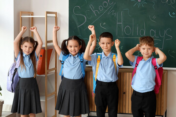 Poster - Cute little pupils near chalkboard in classroom. School holidays concept