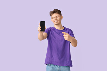 Poster - Young man pointing at mobile phone on lilac background