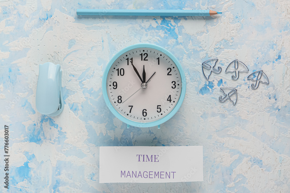 Paper with text TIME MANAGEMENT, alarm clock and stapler on blue grunge background. Top view