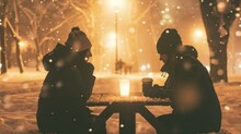 Two Individuals Are Seated At A Wooden Picnic Table Placed In A Snowy Outdoor Setting. They Are Bundled Up Warmly, Appearing To Converse Or Enjoy A Meal Together Despite The Cold Weather.