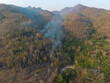High-angle landscape, mountains, dry trees, a forest fire is spreading, smoke rising from the mountains in Chiang Mai, Thailand during summer.