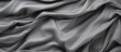 A detailed close-up of a gray fabric with numerous voluminous folds creating a textured surface