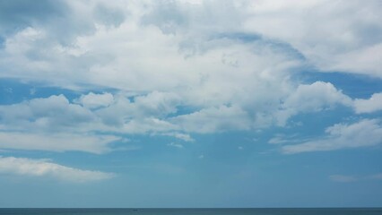 Wall Mural - Timelapse nature landscape of Beach sea and clouds moving in the blue sky in good weather day.Sunlight reflected on the sea surface.Clouds traveling over the wide space of clear blue sky background