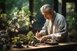 Elderly Asian man engaging in the delicate art of bonsai under warm light.