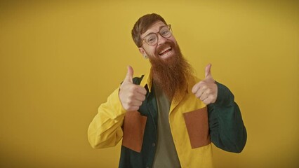 Wall Mural - Cheerful, red-haired guy in glasses and shirt, standing over a yellow backdrop, gives a thumbs-up showing off his winning vibe. right on! he's oozing success, approving with a beaming smile.