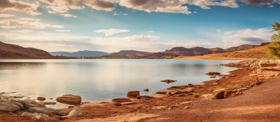 Sticker - The tranquil lake is framed by various rocks and lush green trees, creating a picturesque scene in nature