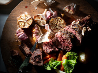 Poster - Cut steak and roasted garlic on a cutting board