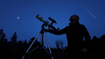 Wall Mural - amateur astronomer looking at the evening skies, observing planets, stars, moon and other celestial 