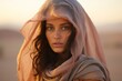 Candid shot of a young Bedouin woman, her veil gently fluttering in the desert breeze, showcasing the delicate intricacies of her pastel-hued garments