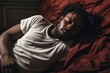Portrait of an African American man, around 35 years old, lying on the bed in the bedroom, holding his stomach due to cramps