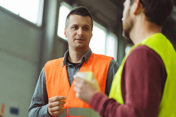 Wall Mural - Successful, professional foreman, worker, engineer talking to employee while standing in warehouse