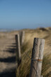 A wooden pile as part of a fence in a dune landscape in the blurred background
