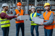 © Maria Vitkovska - Group of successful workers wearing safety helmets and workwear holding boxes, looking away