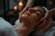 woman lying on massage table with closed eyes and hands of professional spa woman massaging her face in beauty salon