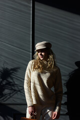 Wall Mural - Studio portrait of beautiful woman with a curly blond hair, posing on gray background.