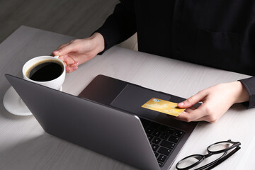 Online payment. Woman with laptop and credit card at white wooden table, closeup