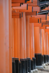 Red pagodas and gates up the mountain in Fushimi Inari-Taisha shinto shrine temple in Kyoto, Japan with traditional architecture buildings, buddha and fox statues decorations and Japanese garden 