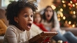 Curly hair multiracial girl surprised face holding a gift. Blurred family member and living room background. 