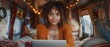 Joyful young mixed-race woman working remotely in RV camper trailer. Concept Remote Work, RV Camper Trailer, Young Woman, Mixed Race, Joyful Attitude