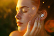 Close up photo of woman with eyes closed listening music with white TWS earbud, warm golden hour
