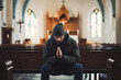 Religious unrecognizable caucasian man sitting alone in small empty church and praying for better future