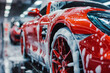 Red Sports car Wheels Covered in Shampoo Being Rubbed by a Soft Sponge at a Stylish Dealership Car Wash. Performance Vehicle Being Washed in a Detailing Studio