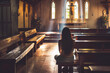 Religious unrecognizable Woman sitting alone in silence in small empty church and praying