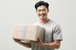 Happy Young Man Carrying a Cardboard Box. Asian man holding package parcel box. Delivery courier and shipping service concept on white background. Generative AI.