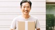 Happy Young Man Carrying a Cardboard Box. Asian man holding package parcel box. Delivery courier and shipping service concept on white background. Generative AI.