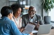 © Ilia Nesolenyi - A mature couple sitting at a table, engaged in a discussion with a financial advisor about retirement planning and investment strategies