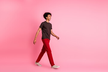 Poster - Full body length photo of positive young man in casual garment steps look empty space new collection isolated on pink color background