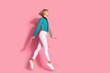 Full size photo of pretty young girl running fast shopping wear trendy striped cyan outfit isolated on pink color background