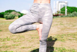 Fototapeta Las - close up detail of an unrecognizable woman doing yoga positions at park, active and healthy lifestyle concept