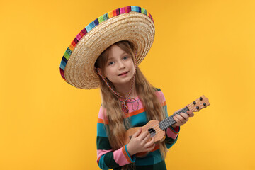 Wall Mural - Cute girl in Mexican sombrero hat playing ukulele on orange background
