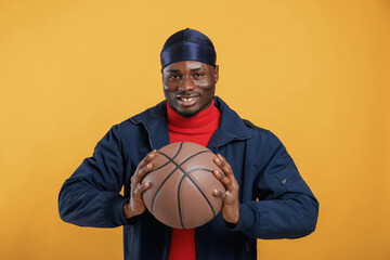 Wall Mural - With basketball ball. Handsome black man is in the studio against yellow background