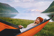 © EVERST - Woman chilling in hammock enjoying nature in Norway tourist traveling solo healthy lifestyle summer vacations with camping gear girl relaxing alone weekend getaway sunset fjord and mountains view