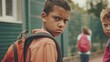 Portrait of angry schoolboy with a backpack in the schoolyard. School bullying concept