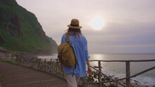 Camera Follows Woman Hiker With Backpack. Traveler Hiker, Enjoys Nature And Life. Traveling In The Mountains, Adventure In Trip. Lifestyle Concept. Woman Walking On Mountain Trail In Madeira