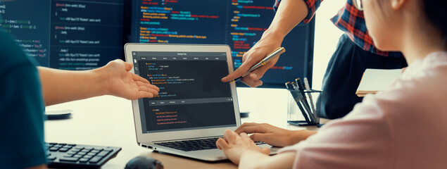 Two smart cooperative computer engineers working together as teamwork to solve program code while computer screen displayed program code. Laptop, web development, programer, java script . Burgeoning.