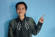 Portrait a handsome Asian man wearing batik shirt pointing finger side