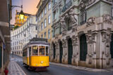 Fototapeta  - Yellow tram on a street with historic buildings in Lisbon, Portugal