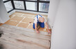© anatoliy_gleb - Top view of man construction worker laying laminate wood plank on floor underlayment in living room. Man installing laminate timber flooring in apartment under renovation.