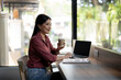 © Wasana - A confident businesswoman enjoys her coffee while working on a laptop in a cafe, a picture of modern professionalism and productivity.