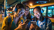 © XaMaps - Friends sharing music from a phone and enjoying together at a bus station with evening lights in the background.