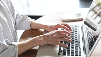 Closeup of a woman's hand typing on a computer for business at an office or cafe No face	