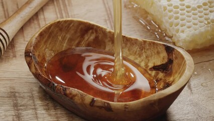 Wall Mural - Drops of honey slowly flowing into a honey bowl, close-up, slow motion. A perfect food background for any of your projects.