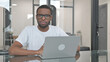 Young African Man Looking at Camera while Working on Laptop in Office