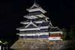 Ancient Japanese Matsumoto Castle at night with a reflection in the moat